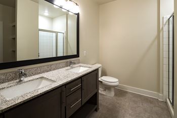 A bathroom with a sink, toilet, standing glass-frame shower and mirror.
